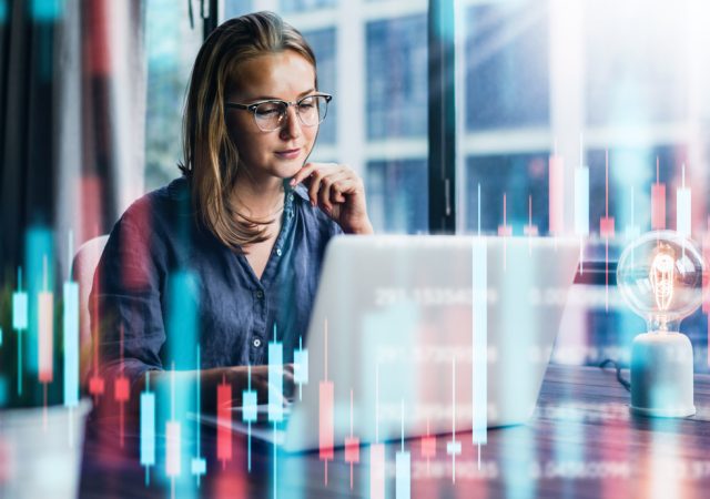 Businesswoman working at modern office.Technical price graph and indicator, red and green candlestick chart and stock trading computer screen background. Double exposure. Trader analyzing data