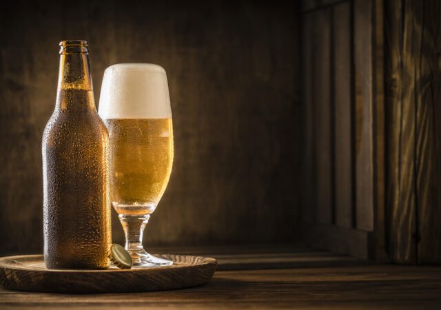 Beer bottle with a drinking glass full of beer on a rustic wooden table